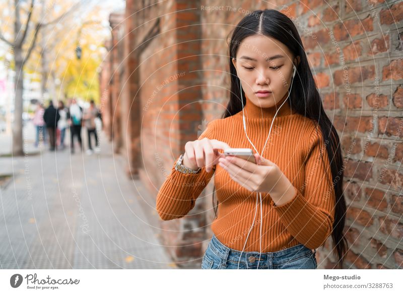 Asian woman using her mobile phone. Lifestyle Joy Beautiful Relaxation Decoration Telephone PDA Technology Internet Human being Woman Adults Street Fashion