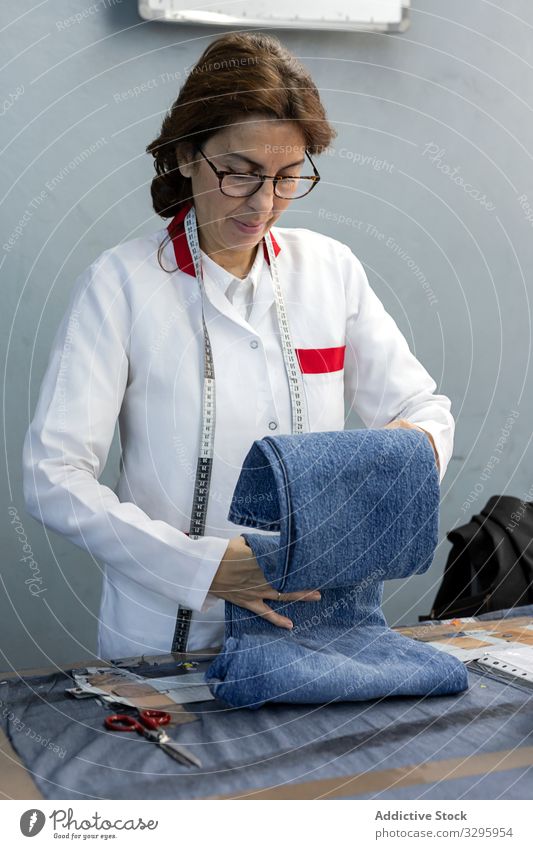 Working woman in textile factory checking industry clothing manufacturing worker machine sewing hands fabric pants blue jeans occupation industrial production