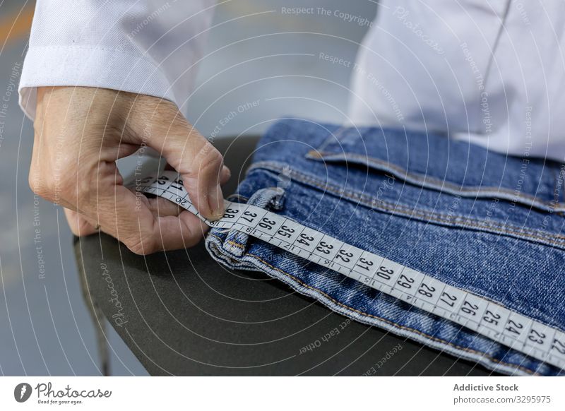 Working woman in textile factory checking industry clothing manufacturing worker machine sewing hands fabric pants blue jeans occupation industrial production