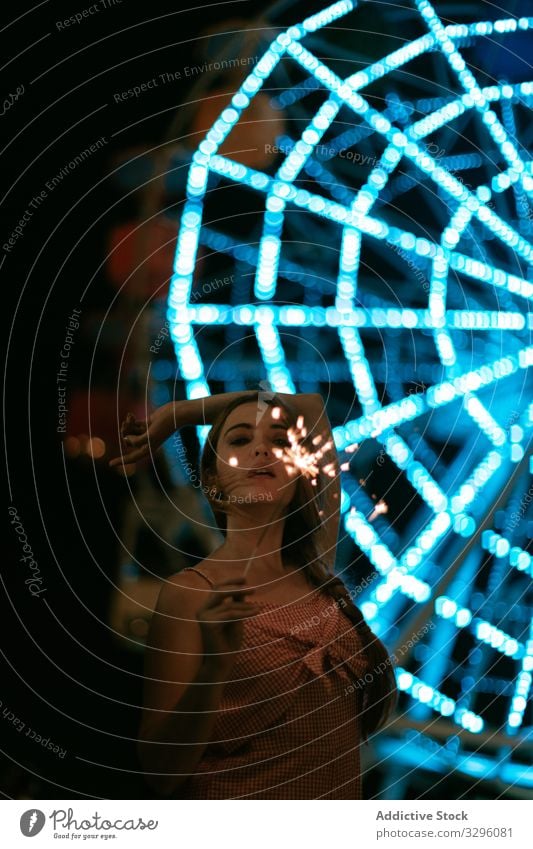 Sensual woman standing in amusement park and holding sparklers sensual enjoy relax funfair happy young millennial teenager carefree light celebration event