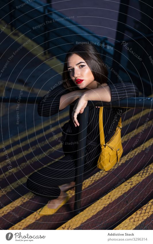 Woman in stylish outfit setting peaky cap right at city street woman fashionable trendy dusk shadow clothing standing young lady brunette accessory modern