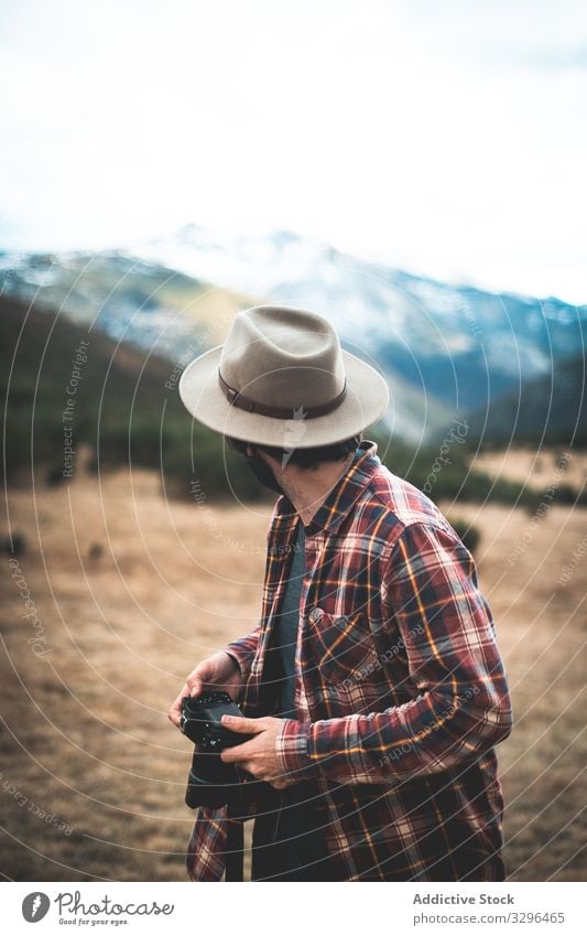 Man with camera in hand looking back at mountains traveler hat photographer nature adventure tourist vacation photography freedom wanderlust extreme