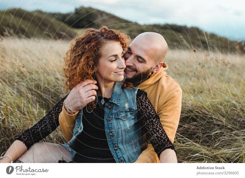 Hipster couple in love sitting in field and enjoying romantic moments embrace nature happy young together grass hug cuddle romance relationship tenderness