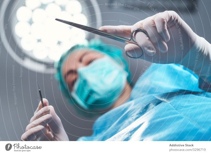 Woman performing surgery in hospital surgeon operating theater lamp tool mask hat woman work doctor healthcare female sterile instrument job uniform medicine