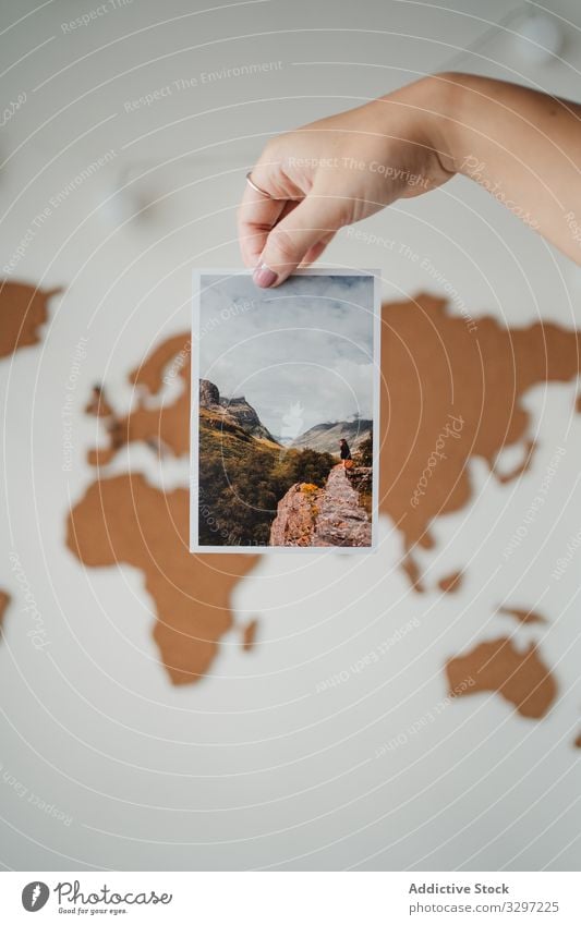Anonymous woman holding picture in front of world map postcard photo global image information female travel lifestyle journey planet earth object geography