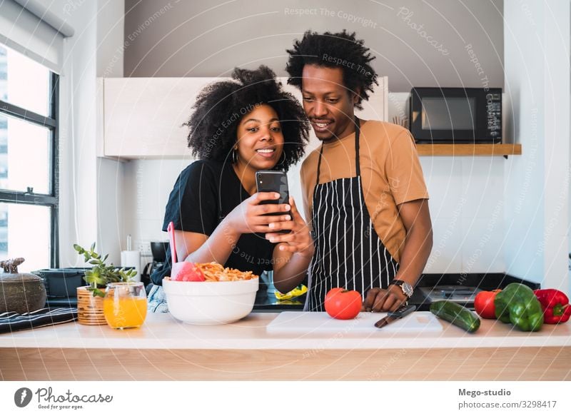 Afro couple cooking together and using phone at home. Lifestyle Happy Leisure and hobbies Flat (apartment) House (Residential Structure) Kitchen Telephone