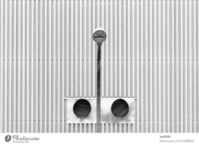 symmetrical view of a street lamp in front of two ventilation tubes with corrugated sheet metal facade Industrial plant Manmade structures Building