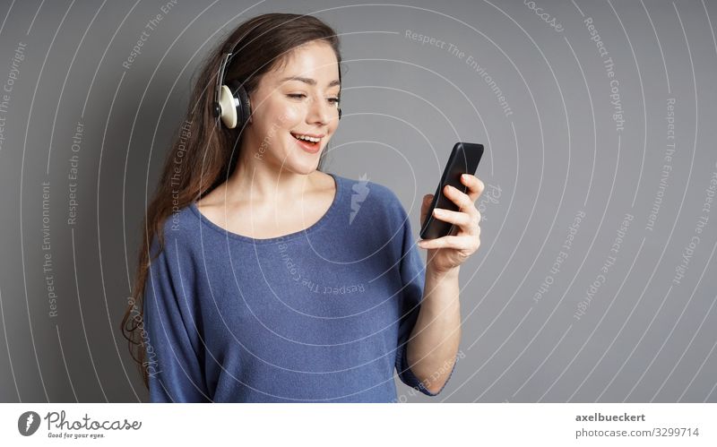 young woman streams music from smartphone via headphones Lifestyle Joy Leisure and hobbies Entertainment Music Cellphone MP3 player PDA Human being Feminine