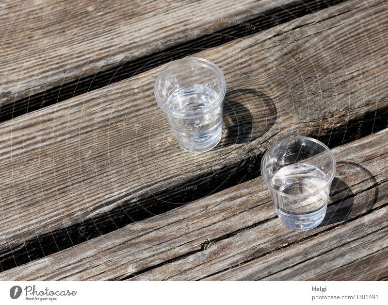 two plastic cups with liquor stand on a wooden table Beverage Alcoholic drinks Spirits Glass Wood Stand Drinking Wait Authentic Simple Small Delicious Brown