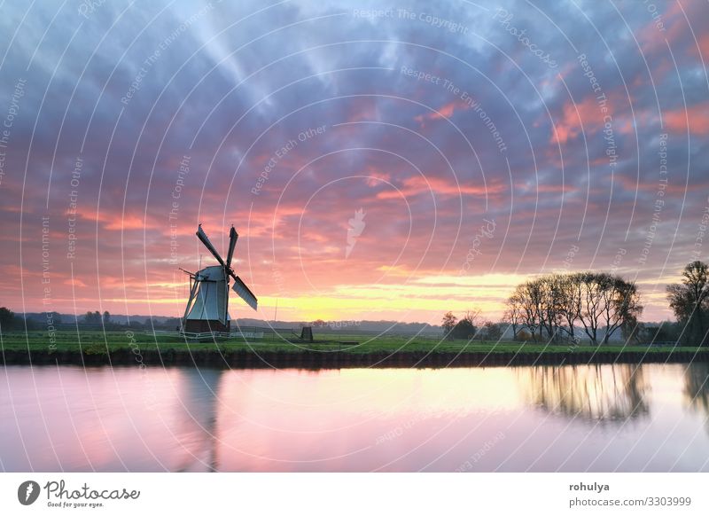 dramatic purple sinrise over windmill by river Dutch Holland Netherlands white canal water sunrise dawn morning horizon sky cloud cloudscape red countryside