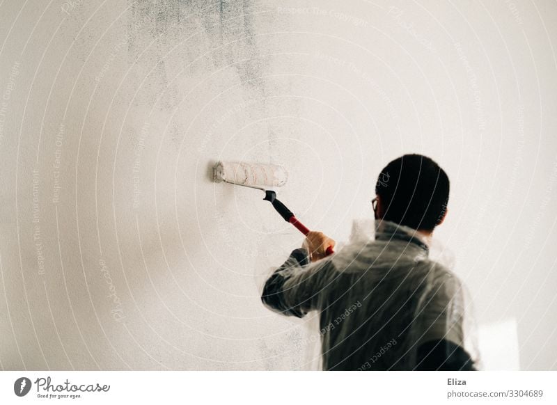 A man paints a wall with a paint roller in white color Painting (action, work) color roll White Redecorate Colour Painter Extract Wall (building) Paintwork