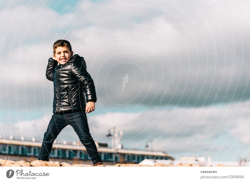 Cute kid throwing rocks with cloudy sky background Lifestyle Joy Happy Leisure and hobbies Playing Vacation & Travel Adventure Beach Ocean Winter Sports Child