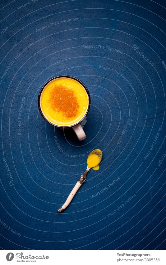 Turmeric latte on a blue table. Healthy drink. Yellow milk cup Herbs and spices Beverage Hot drink Natural Curcuma Longa above view antioxidant Aromatic