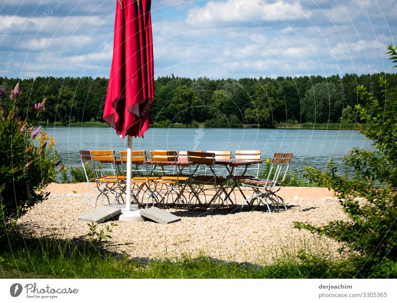 Pure idyll. A lake , in front of a parasol with a group of chairs in a circle. In front green and in the background forest. Joy Relaxation Summer Environment
