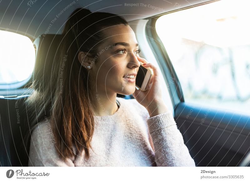 Young beautiful woman with ponytail talking on the phone in the back seat of car female mobile phone business pretty urban tied-up girl people cute drive