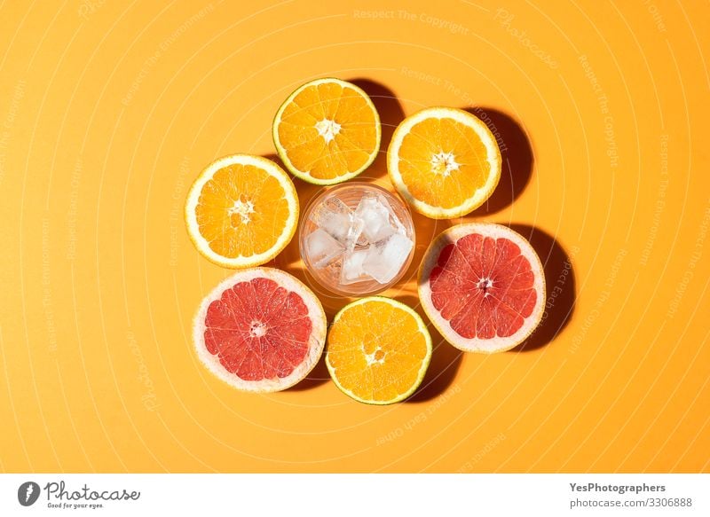 Citrus fruits and glass with ice in sunlight. Fruit Orange Breakfast Organic produce Vegetarian diet Diet Cold drink Healthy Eating Fresh Bright Red above view