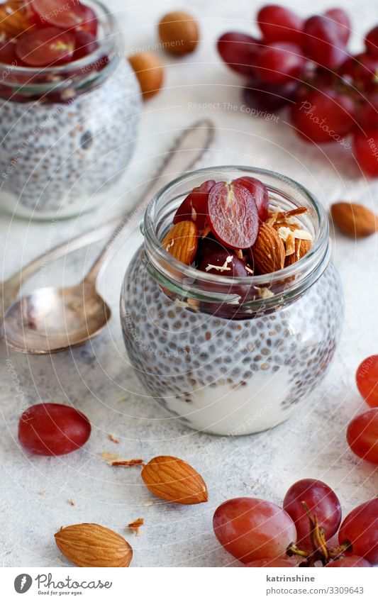 Chia pudding parfait with red grapes and almonds Yoghurt Fruit Dessert Eating Breakfast Diet Spoon White jar chia Bunch of grapes nuts Pudding seed chia seeds