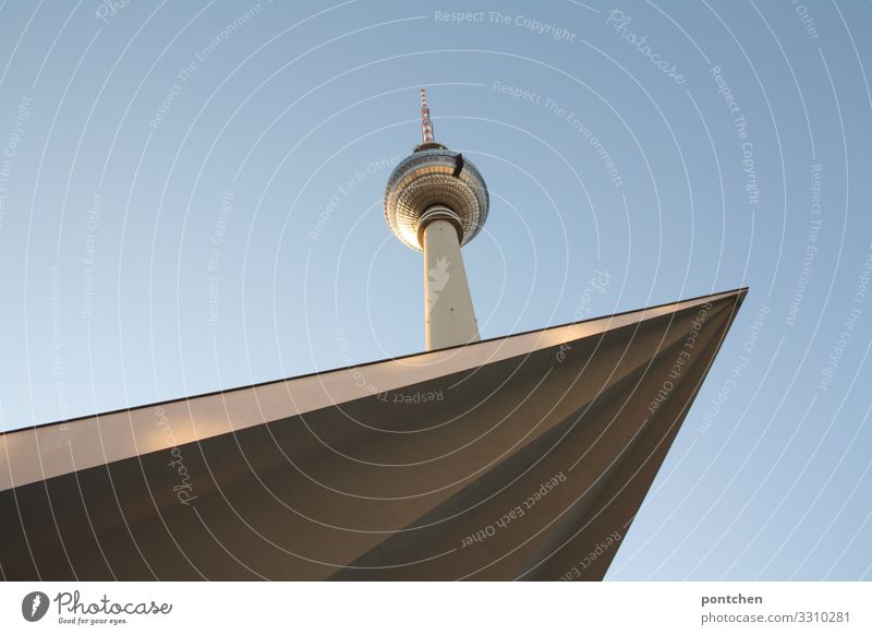 TV tower berlin in front of a blue sky. Tip of a roof juts into the picture. architecture. Landmark. Television tower Tourist Attraction Tall Point Colour photo