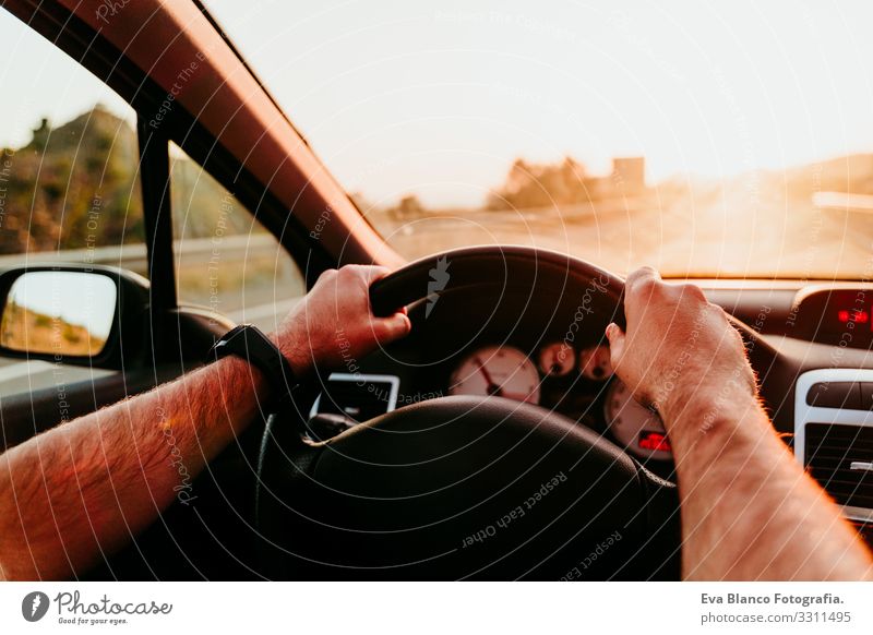 unrecognizable man holding wheel and driving at sunset. travel concept Man Driving Car Sunset Street Vacation & Travel Trip Caucasian Unrecognizable pov