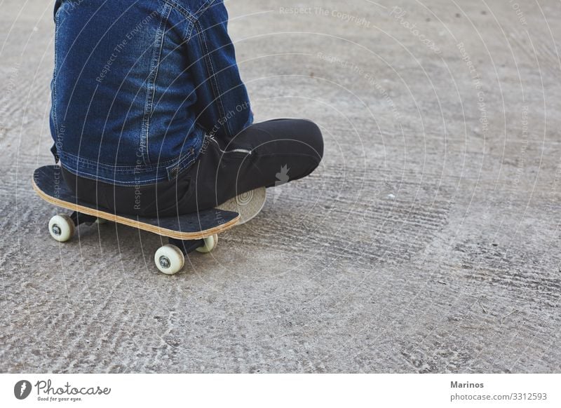 Kid skateboarder sitting on his skateboard. Lifestyle Joy Sports Child Human being Boy (child) Youth (Young adults) Park Street Jeans Skateboard Skateboarding