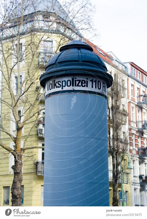 People's Police written on advertising pillar Advertising Industry Winter Tree Prenzlauer Berg Facade Advertising column Digits and numbers Signage Authentic
