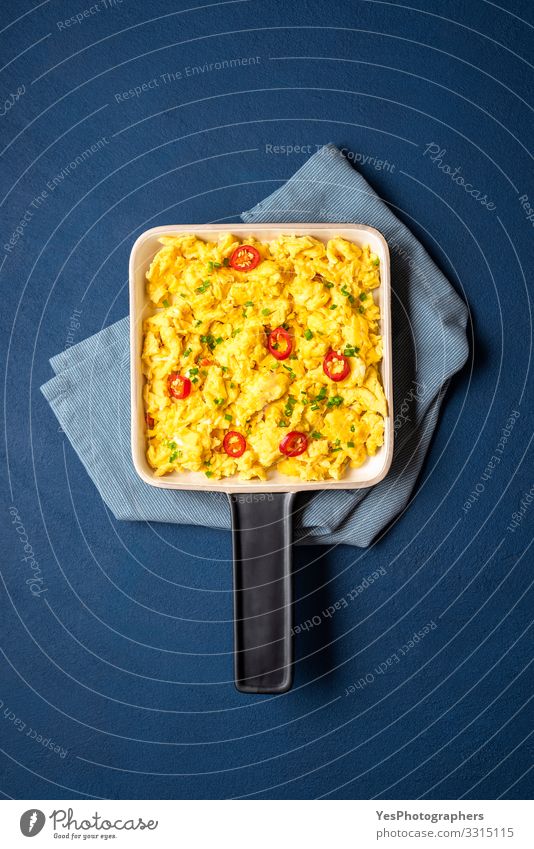 Scrambled eggs pan close-up on blue table. Food Breakfast Lunch Healthy Eating Kitchen Fresh Blue Yellow Tradition above view Blue background blue phantom