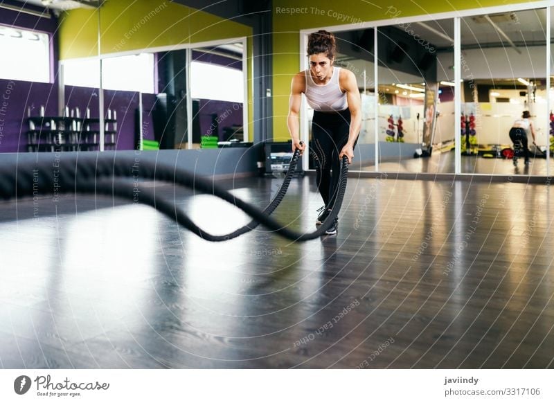 Young and athletic woman using training ropes in a gym. Lifestyle Personal hygiene Body Wellness Club Disco Sports Rope Human being Feminine Woman Adults