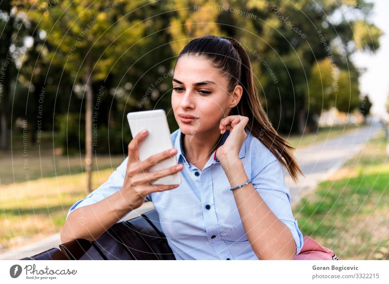 Pretty young sitting on a bench with mobile phone Lifestyle Happy Beautiful Summer Sun Telephone PDA Technology Human being Young woman Youth (Young adults)