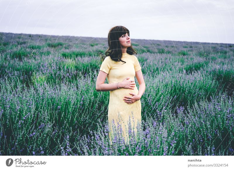 Lovely young woman in her first month of pregnancy pregnant brunette lavender flowers spring weeks one month two beggining floral field nature natural real