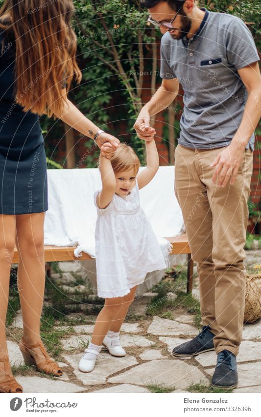 Little blonde girl playing and holding her young parents hand. Playing Freedom Garden Wedding Parenting Child Baby Man Adults Parents Mother Father