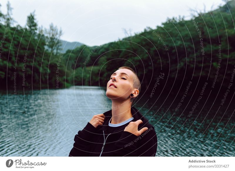 Unconventional female enjoying rain near natural pond woman nature freedom informal sensual provocative short hair piercing casual young skinhead green plant
