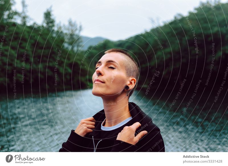 Unconventional female enjoying rain near natural pond woman nature freedom informal sensual provocative short hair piercing casual young skinhead green plant