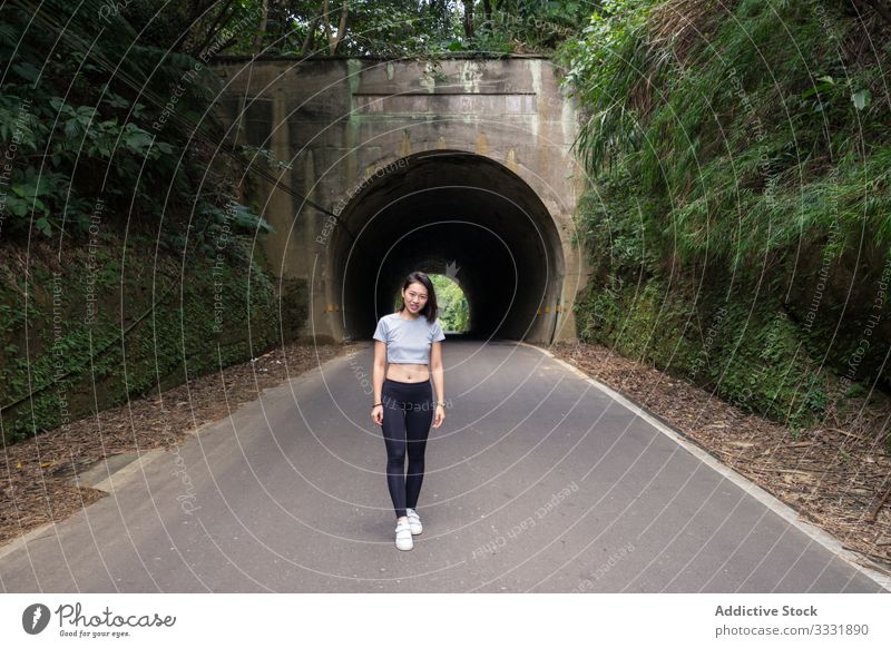 Satisfied female traveler during walk in countryside walking tunnel sportive plants green woman asian young smile laugh enjoy rout road destination explore