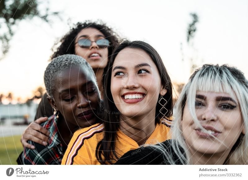 Diverse group of smiling women hugging together on lawn friend laughing cuddling casual fun young female embracing diverse multiethnic multiracial cheerful