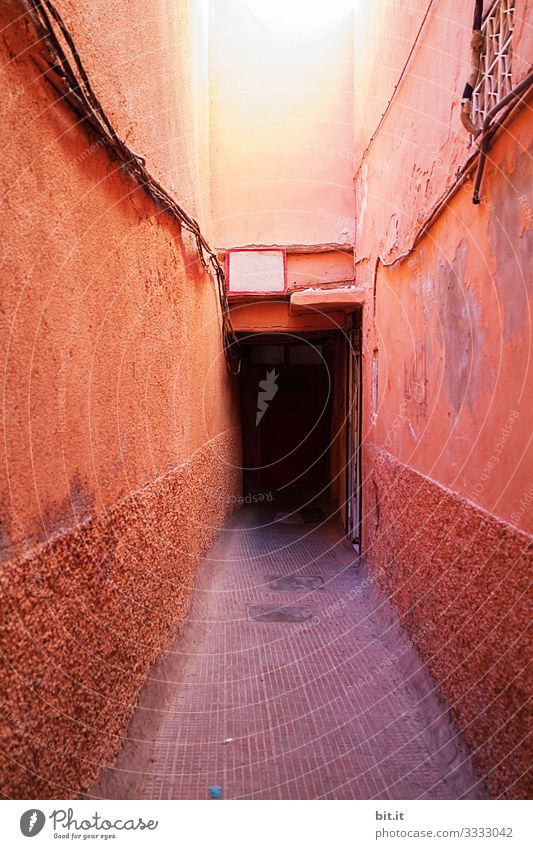 Dark, long, hidden, old, gloomy, dangerous house entrance, behind, between beautiful, colorful, orange, red, mediterranean, narrow, narrow walls, wall, facade on vacation, holidays, travel in Morocco, Africa. architecture.