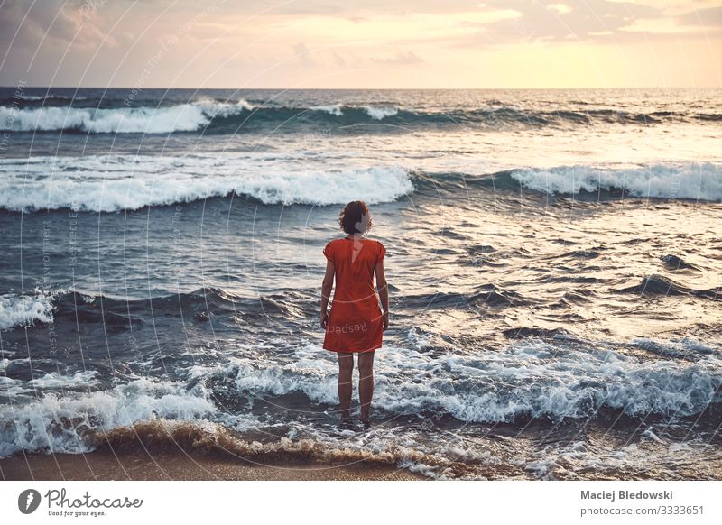 Woman in orange dress standing still in the rough ocean at sunset Lifestyle Relaxation Leisure and hobbies Vacation & Travel Tourism Trip Adventure