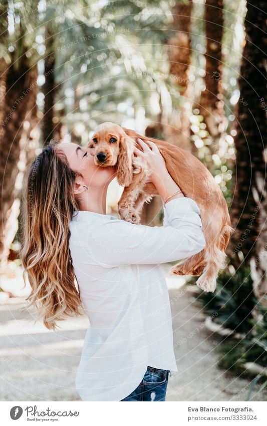 young woman and her cute puppy of cocker spaniel outdoors in a park Woman Dog Pet Park Sunbeam Exterior shot Love Embrace Smiling Rear view Kissing Breed