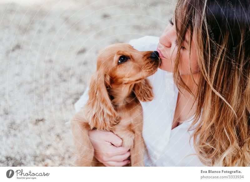 young woman and her cute puppy of cocker spaniel outdoors in a park Woman Dog Pet Park Sunbeam Exterior shot Love Embrace Smiling Rear view Kissing Breed