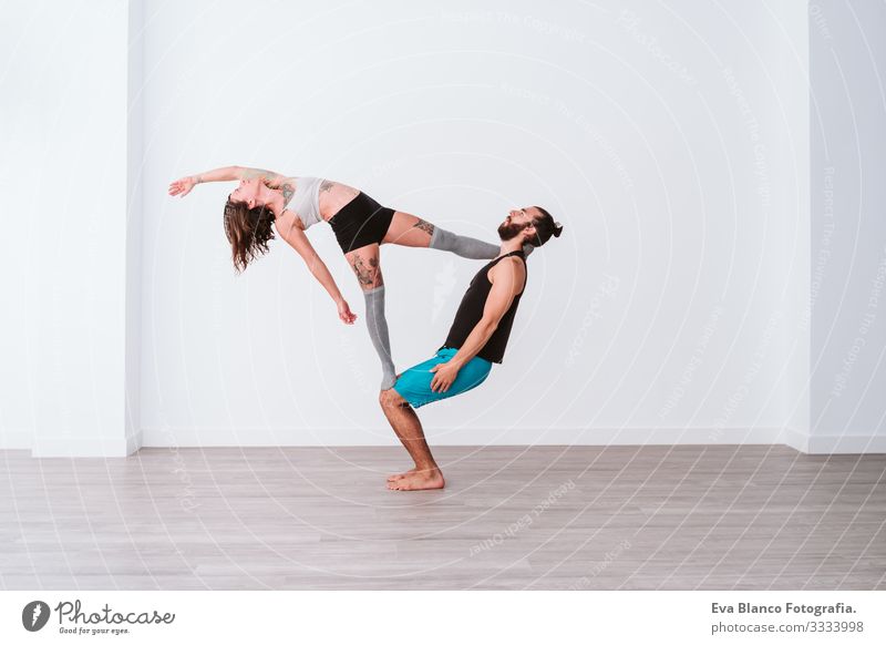 young couple Couple practicing acro yoga in white studio or gym. Healthy lifestyle Yoga Sports Gymnasium indoor Man Power Human being human relationships