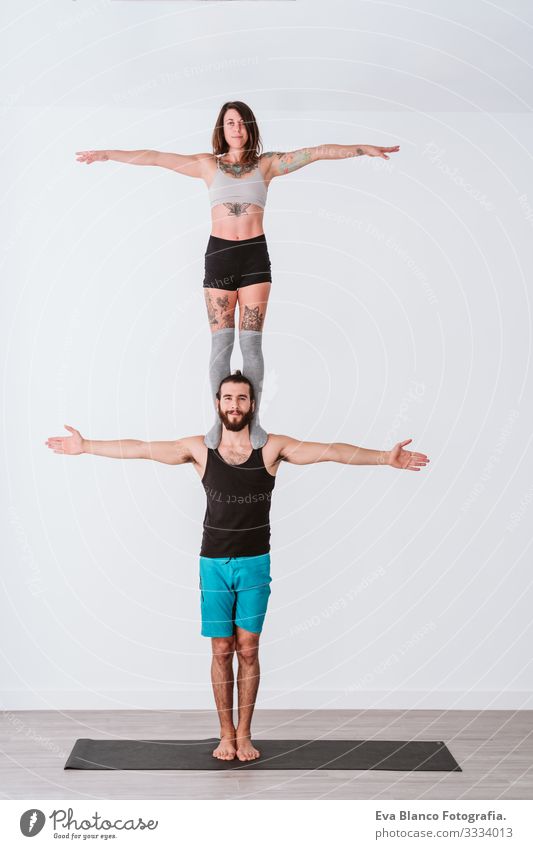 young couple Couple practicing acro yoga in white studio or gym. Healthy lifestyle Yoga Sports Gymnasium indoor Man Power Human being human relationships