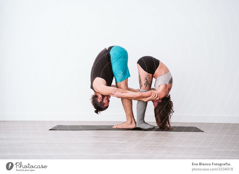 young couple Couple practicing acro yoga in white studio or gym. Healthy lifestyle Yoga Sports Gymnasium indoor Man Power Human being human relationships