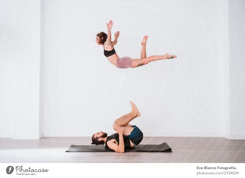 young couple Couple practicing acro yoga in white studio or gym