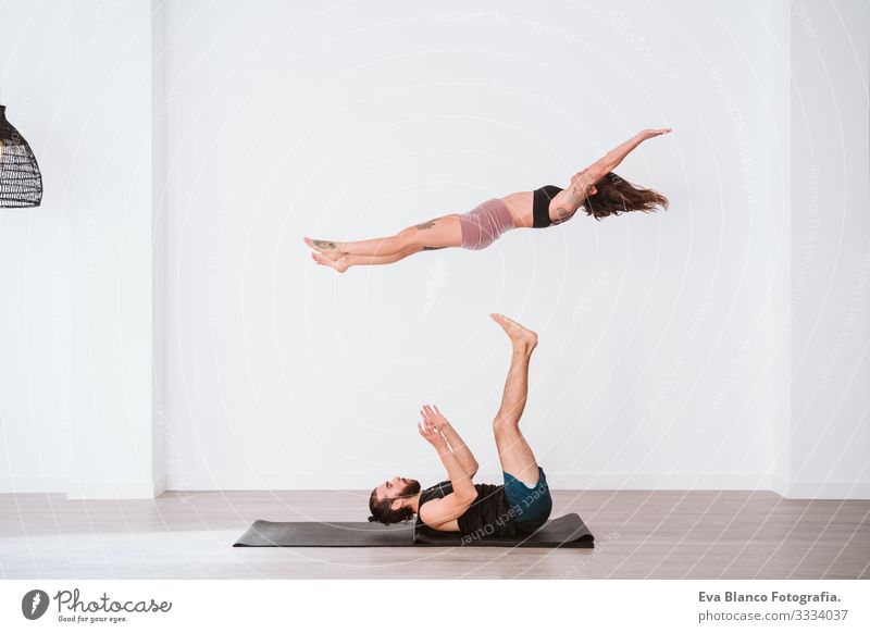 Man and Woman Doing Acro Yoga or Pair Yoga Indoor Stock Photo