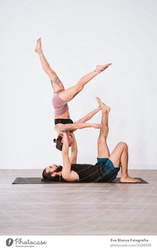 young couple Couple practicing acro yoga in white studio or gym. Healthy lifestyle Yoga Sports Gymnasium indoor Man Power Human being human relationships