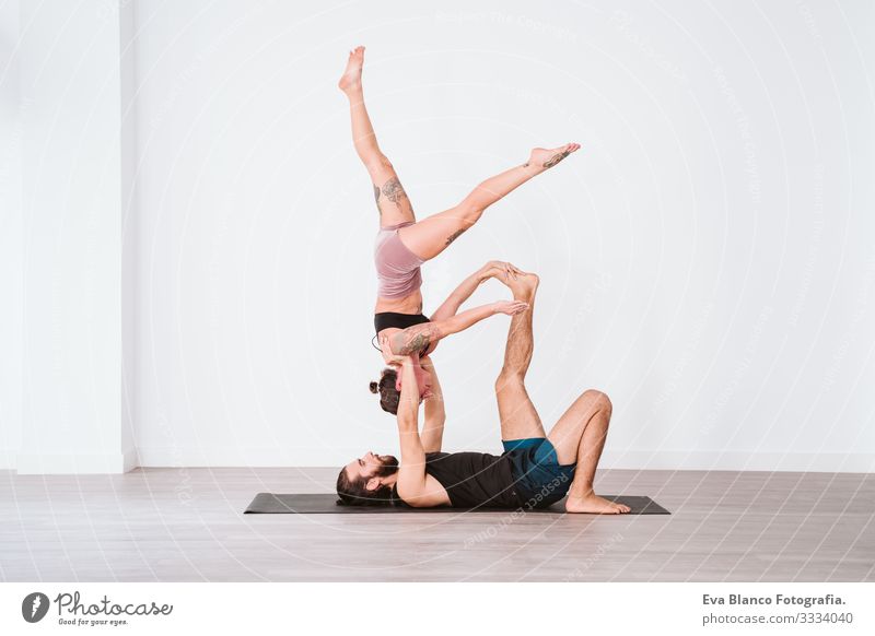 Two sporty girl on white background doing acroyoga, yoga with