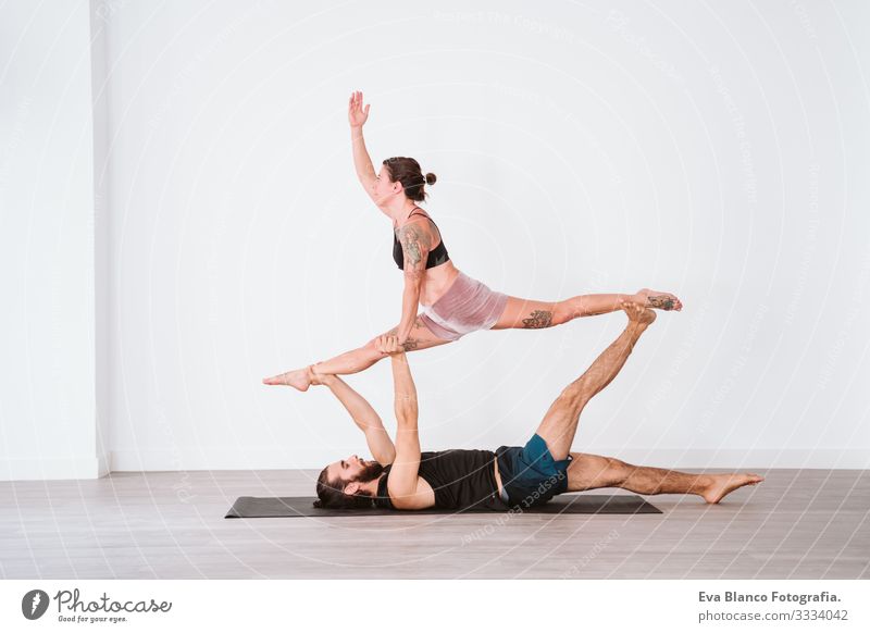 young couple Couple practicing acro yoga in white studio or gym. Healthy lifestyle Yoga Sports Gymnasium indoor Man Power Human being human relationships