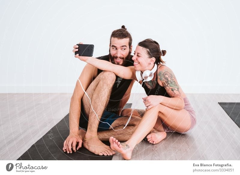 two friends at the gym taking a selfie with mobile phone and headset and having fun. Sport and technology concept Couple Friendship Youth (Young adults) Man