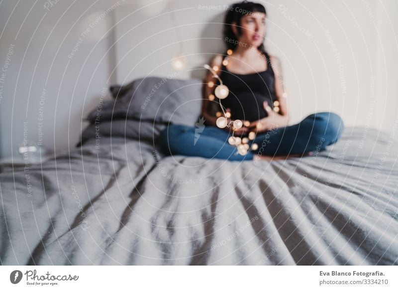 young pregnant woman at home holding a garland of lights Pregnant Woman Home Paper chain Light Christmas & Advent Smiling Happy Portrait photograph