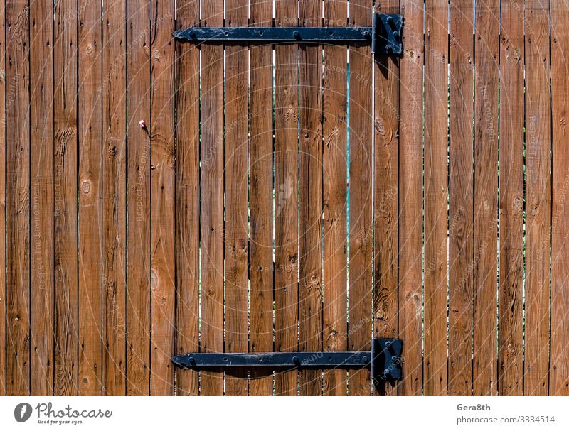 texture wooden fence with a wooden door on iron hinges Wood Brown billet Fence natural tree Consistency Wooden door Colour photo Exterior shot Pattern Day