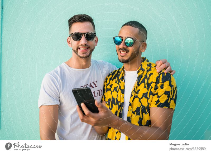 Gay couple spending time together while using phone. Lifestyle Happy Leisure and hobbies Freedom Cellphone PDA Human being Masculine Homosexual Man Adults